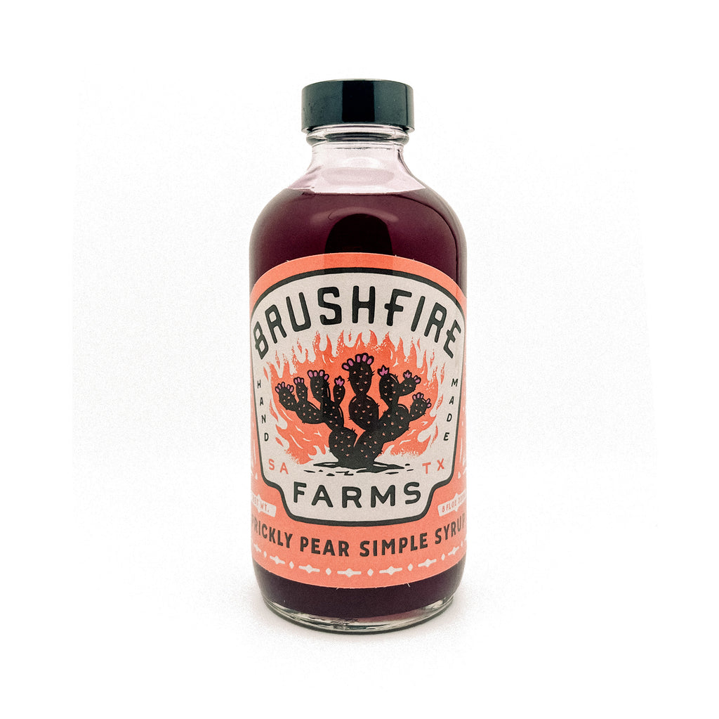 Prickly Pear Simple Syrup in a glass bottle with a vibrant label featuring cacti and Brushfire Farms branding.
