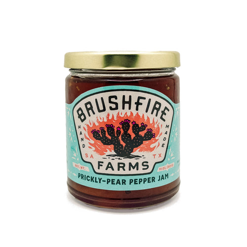 Jar of Brushfire Farms Prickly Pear Pepper Jam featuring a colorful label with a cactus design and gold lid.