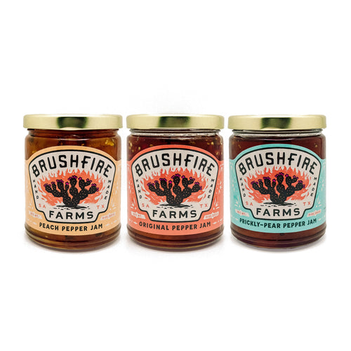 Three jars of Brushfire Farms pepper jams: peach, original, and prickly pear, showcasing vibrant colors and labels.