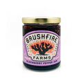 Jar of Brushfire Farms Blackberry Pepper Jam featuring a vibrant label with a cactus design, highlighting its Texas roots.