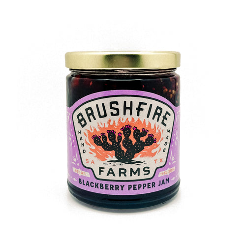 Jar of Brushfire Farms Blackberry Pepper Jam featuring a vibrant label with a cactus design, highlighting its Texas roots.