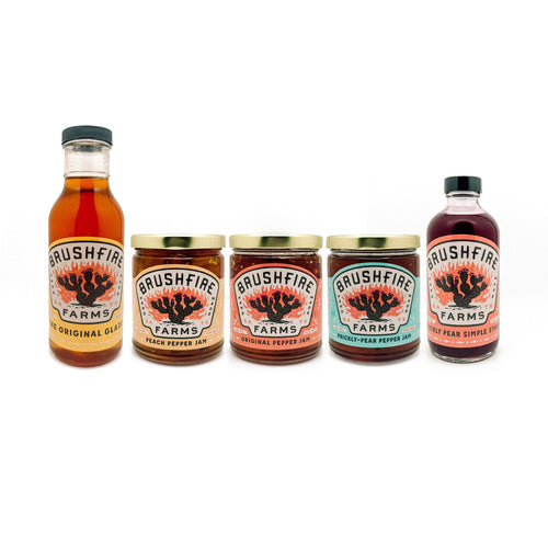 Assorted Brushfire Farms products including El Jefe original glaze, pepper jams, and prickly pear syrup in jars.
